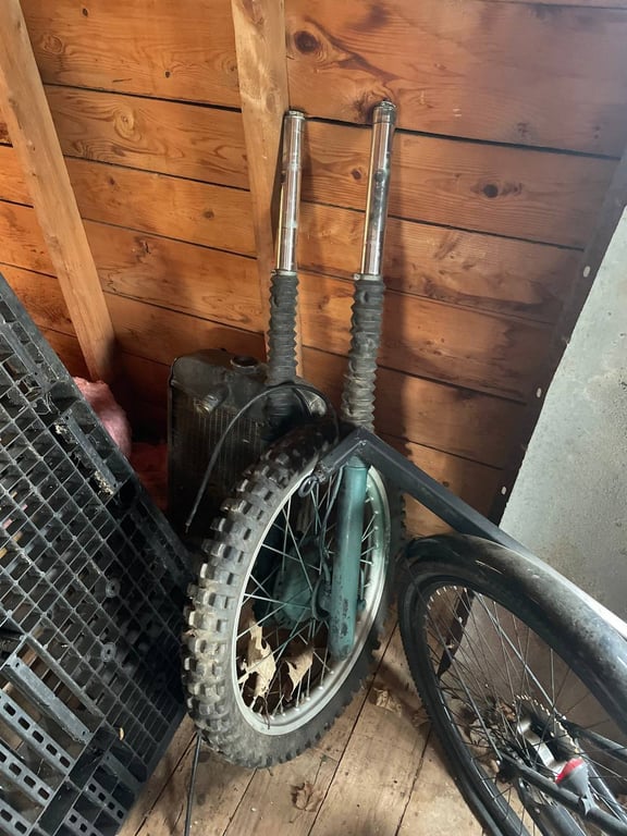1979 Kawasaki KDX400-A1, before restoration: wheel leaning against a wall